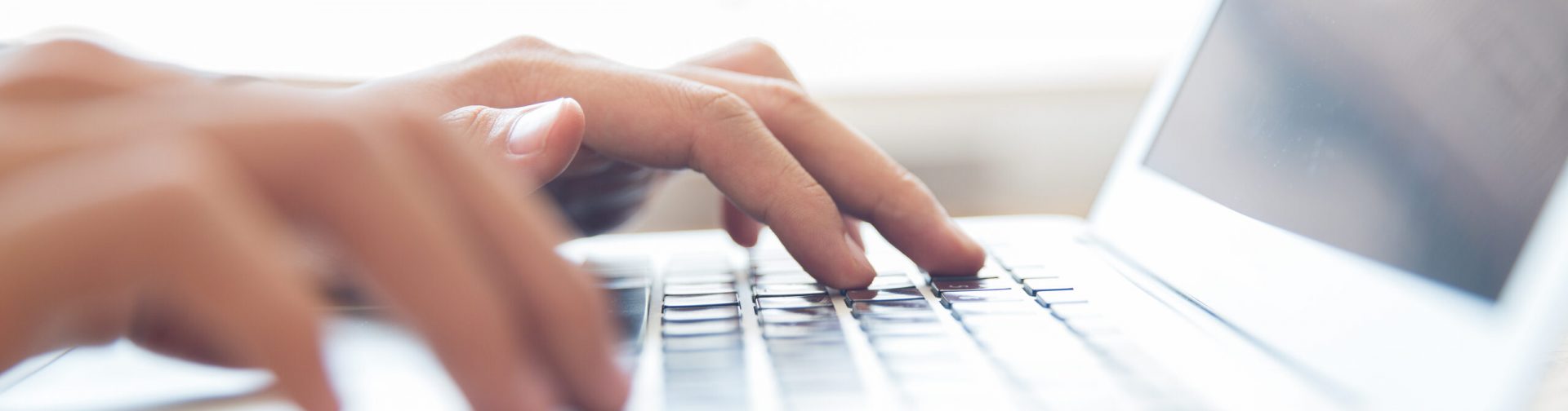 Close-up of male hands typing on laptop keyboard indoors. Businessman working in office or student browsing information